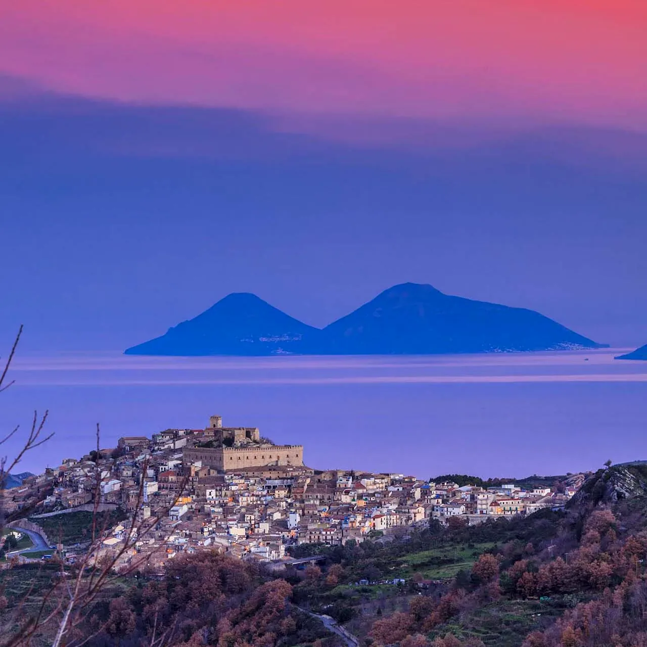 Il borgo di Montalbano Elicona al tramonto con le isole Eolie sul mare
